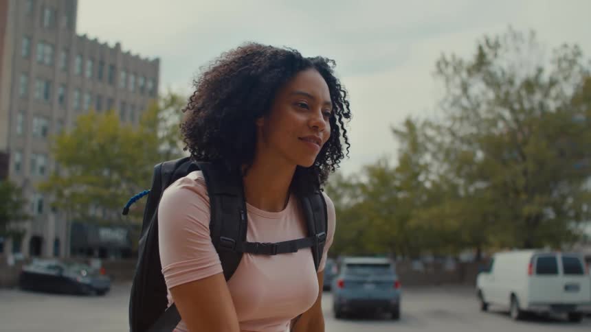 Black woman wearing backpack walks through car park