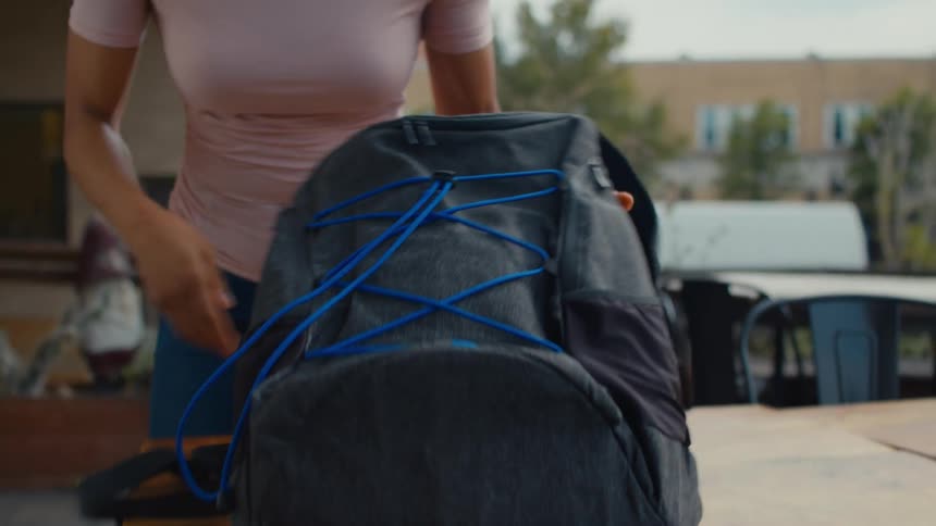 Young woman places a backpack over a restaurant table