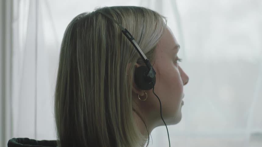 Lateral closeup of a womans face closing her eyes and listening to music