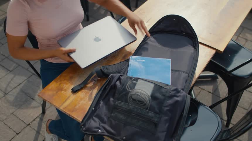 Lady sitting at the outdoor dining table brought out an apple laptop and a book from a backpack