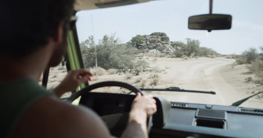 A man driving on a sandy road at midday