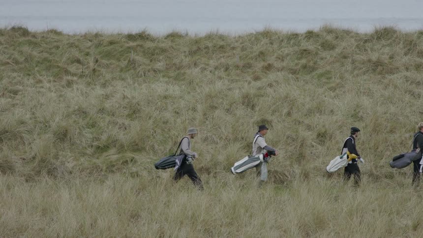 Four men walking in a natural environment with golf equipment