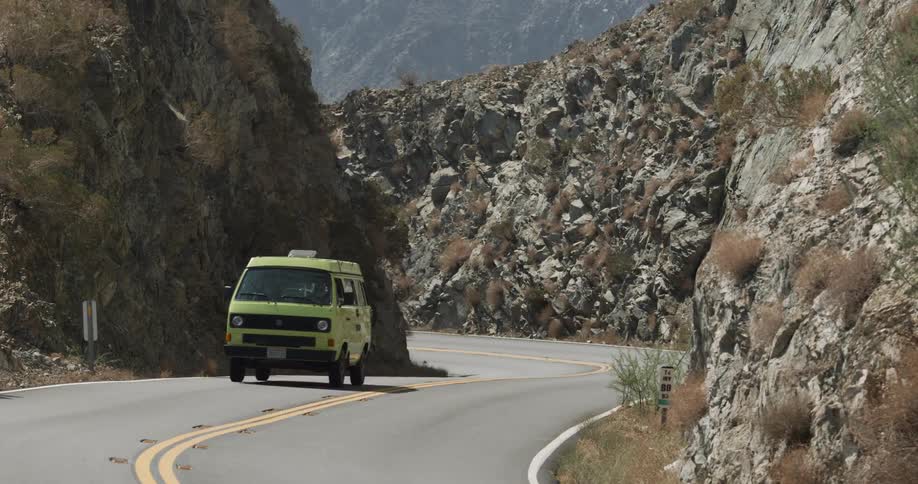 Green van drives on a road through the mountains