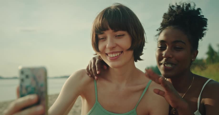 Couple of happy friends talk on a video call from the beach