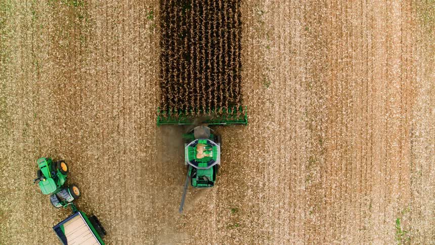 Birds eye view of combine finishing wheat harvest on iconic Midwestern family farm