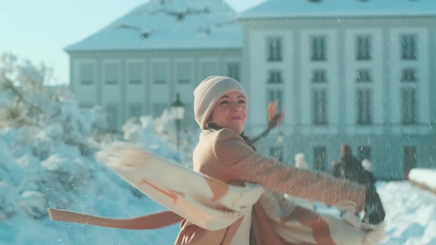 Woman throws snowball before walking toward building during winter snowfall