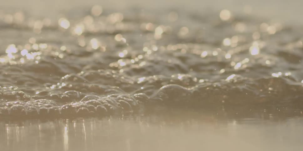 Water sparkles in the sunshine as it runs up on the shore