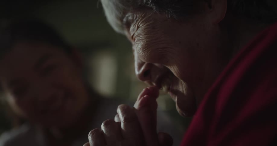 Mother smiles as grandmother kisses childs foot