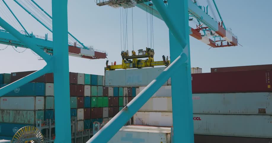 A crane loads a shipping container onto a cargo ship on a clear day