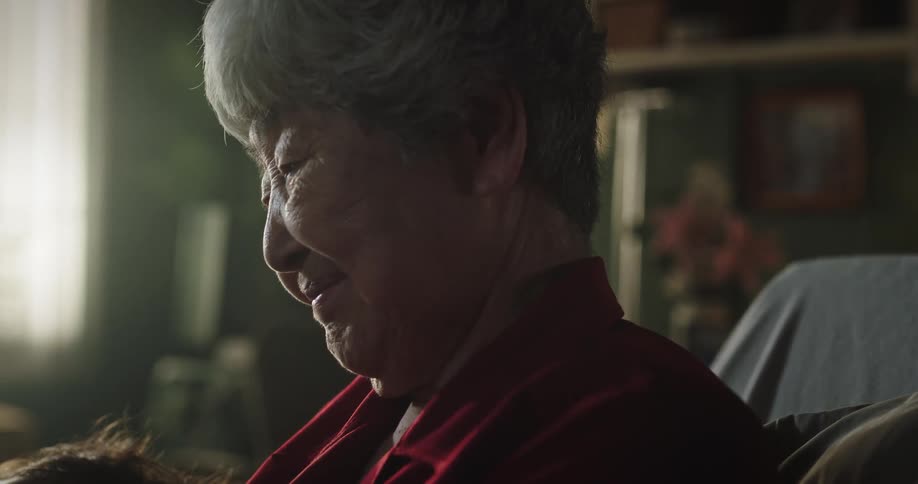 Grandmother holding her sleeping baby grandson in her arms