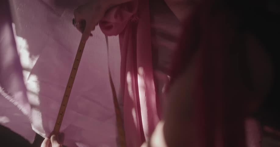 Two female designers measure cloth with measuring tape