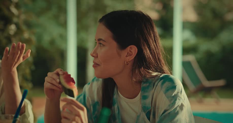 Friends sitting at a table drinking and eating watermelon