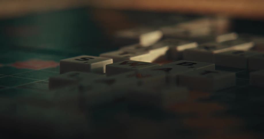 A person forms a word with tiles on a scrabble game board