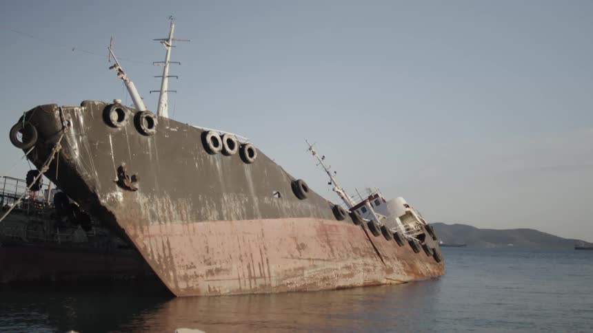 Rusty old ship tilted sideways leaning against the dock
