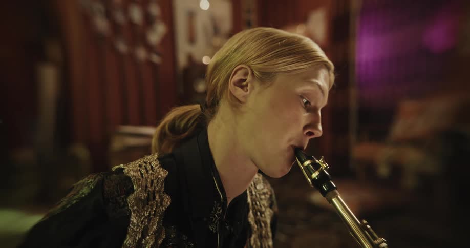 A male saxophone player blows into his instrument while concentrating