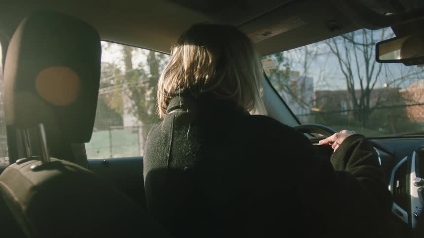 Woman sitting in the car and angrily slapping the steering wheel