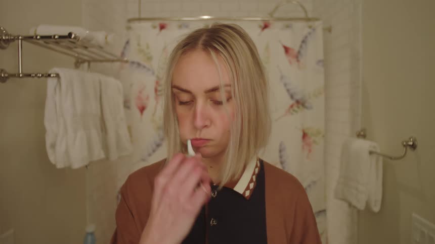 Portrait of a blonde woman in the bathroom brushing her teeth