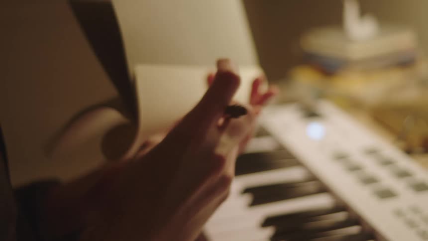 Closeup of a womans hands picking up a notebook and writing