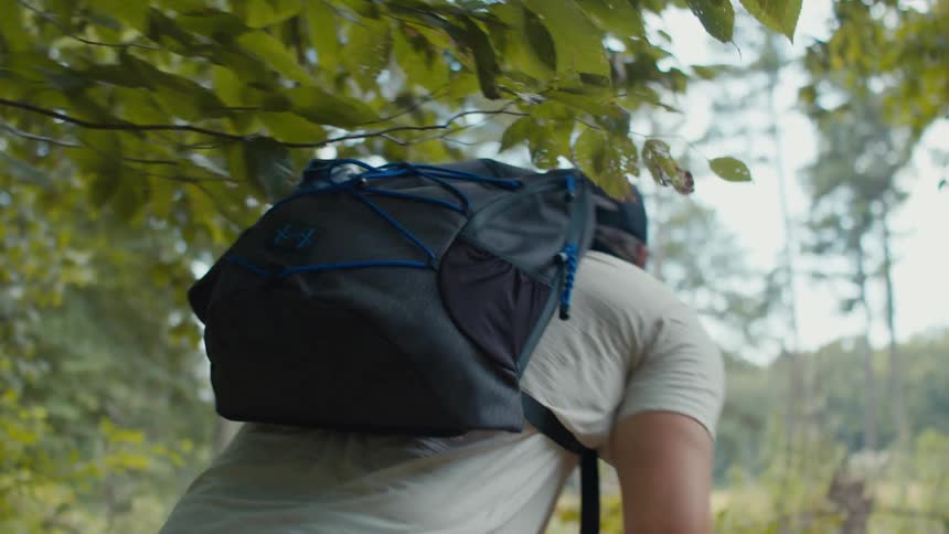 A man backpacks through a forest on a summer day