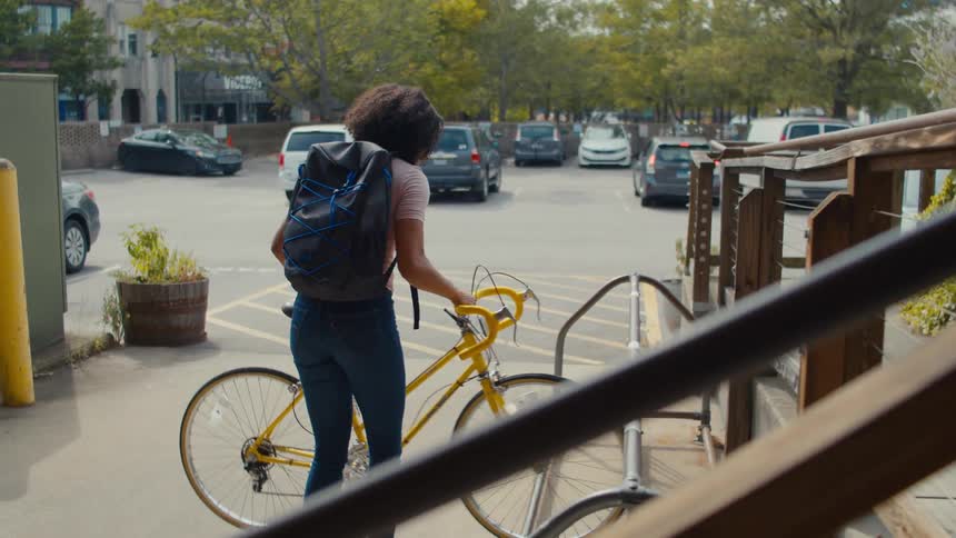 Female teen put her bicycle in a parking spot and walked inside a building at midday
