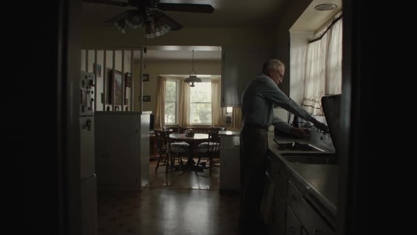 A man filling a glass with water from the kitchen tap