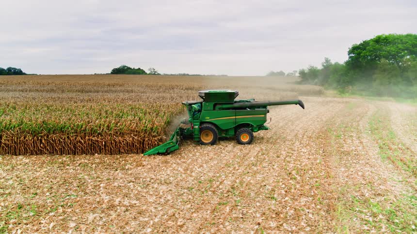 John Deere harvester collecting harvest on commercial agricultural land in America's heartland