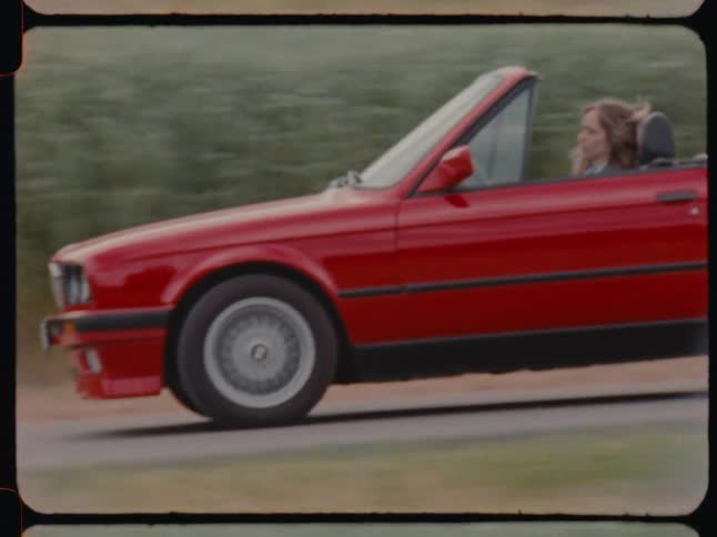 A woman drives her convertible down the road