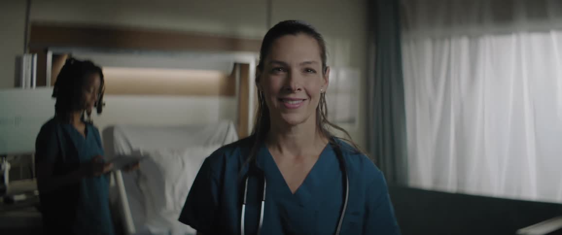 Portrait of a smiling female nurse with another nurse behind her working on a tablet