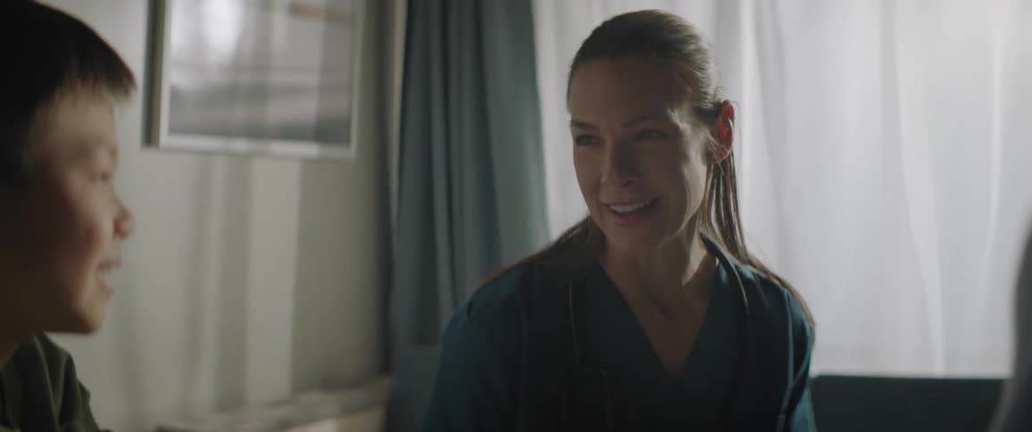 Smiling nurse talking to a boy in a room