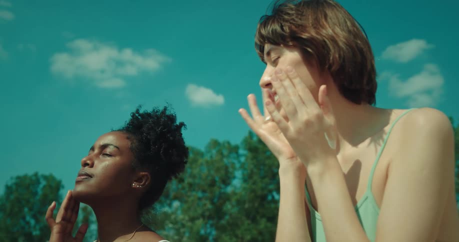Portrait of two women applying sunscreen to their faces at the beach