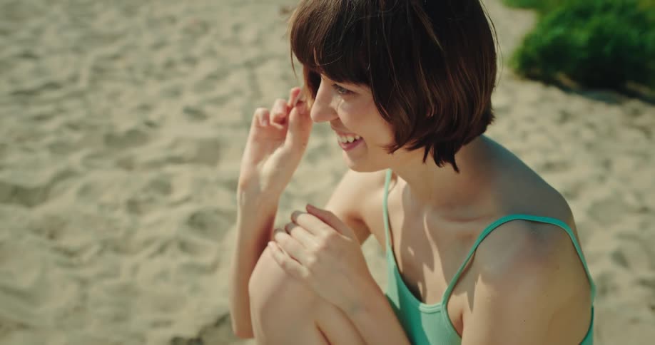 Two women wearing bikinis play cards on the beach near the sea