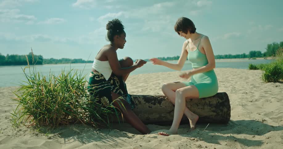 Two women are playing cards by the river
