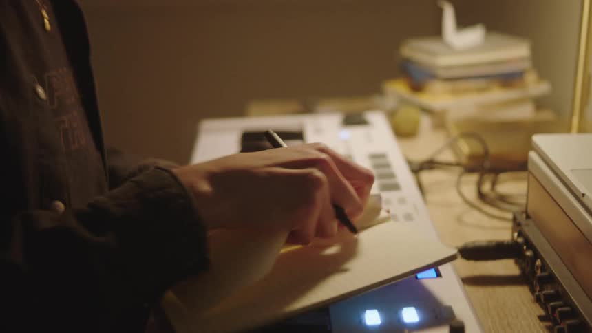A nervous woman writing a song in a notebook