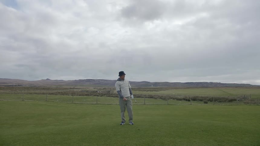 Man swings swings a club to hit a golf ball and walks off to find it