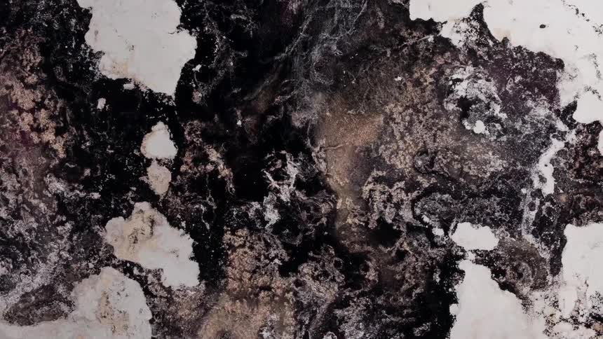 Extreme closeup of a dense liquid with white powder mixing in an abstract motion