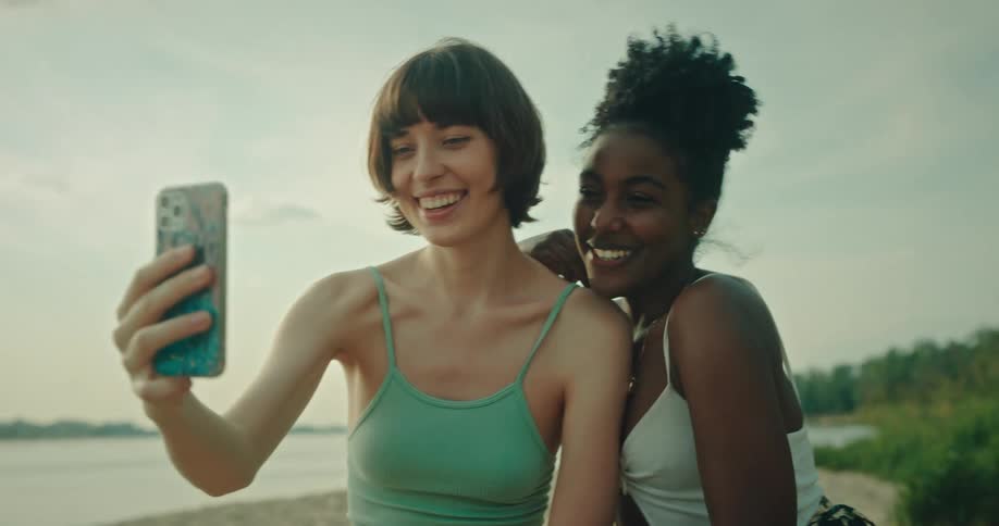 Friends taking selfie on the beach during sunset