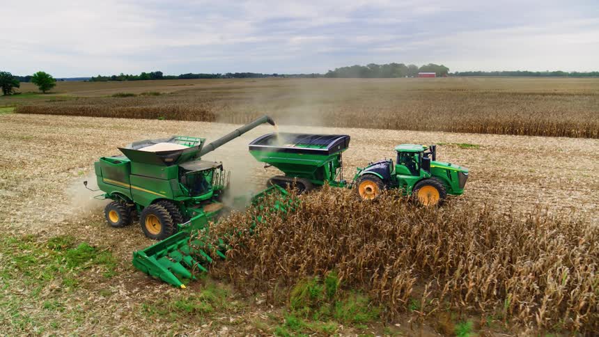 Tractor and combine working in tandem to harvest fields in the heat of the day