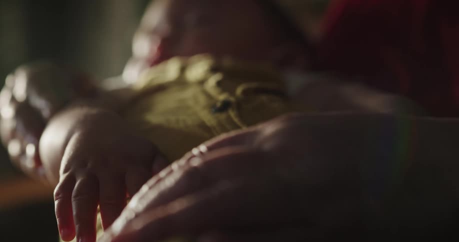 Closeup of the grandmothers arms holding her sleeping baby grandson