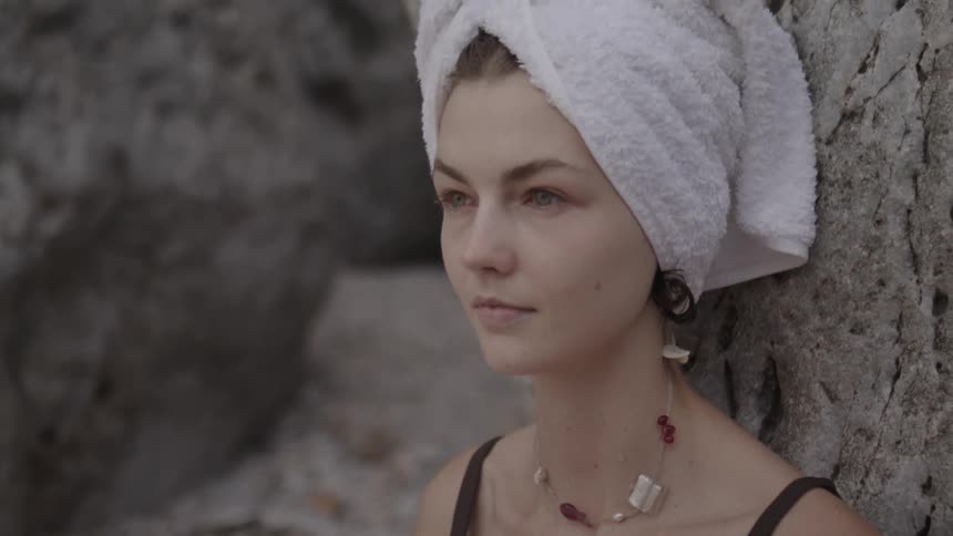 Portrait of a woman sitting on the sand with a towel on her head