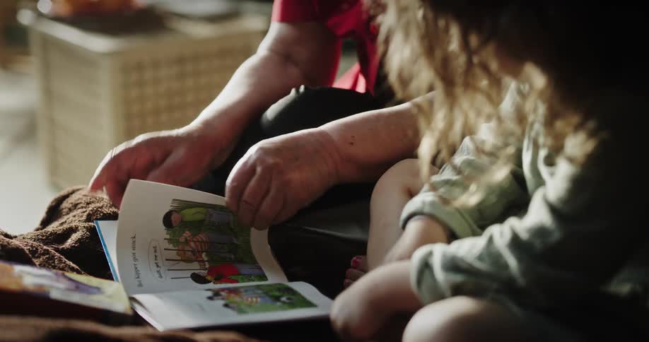 A grandmother reading a story book to her granddaughter