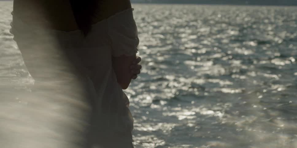 Person standing close to the water's edge watching the ripples