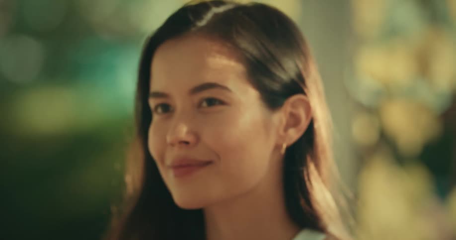 A woman with straight hair and earrings engages in conversation attentively listening and responding to the other person