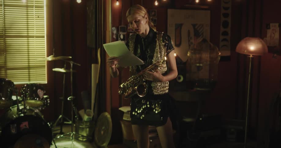 Blonde female plays saxophone indoors