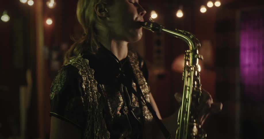 Woman plays saxophone while standing in music room