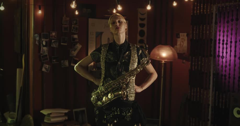Blonde female plays saxophone indoors