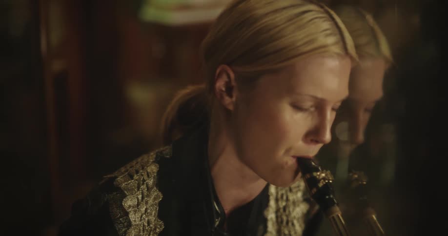 Woman plays the saxophone with her eyes closed conveying a lot of emotion
