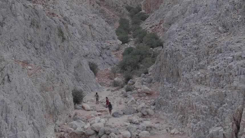 People walking among the rocks of a valley during the day