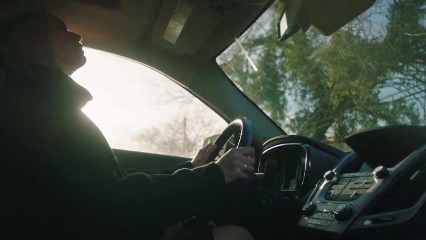 Woman sitting in the front seat with hands on the steering wheel looking frustrated and taking a deep breath
