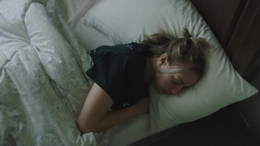 Woman lying in bed checks smartphone and gets up