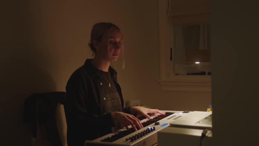 A woman is playing an electric keyboard and composing music